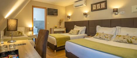 A hotel room with two beds, a desk, a chair, a window, an air conditioning unit, and a wall-mounted artwork.