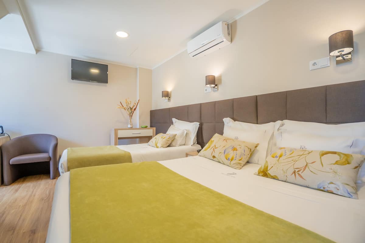 Ein Hotelzimmer mit zwei Betten, einem Fernseher, einer Klimaanlage und einer Lampe.
