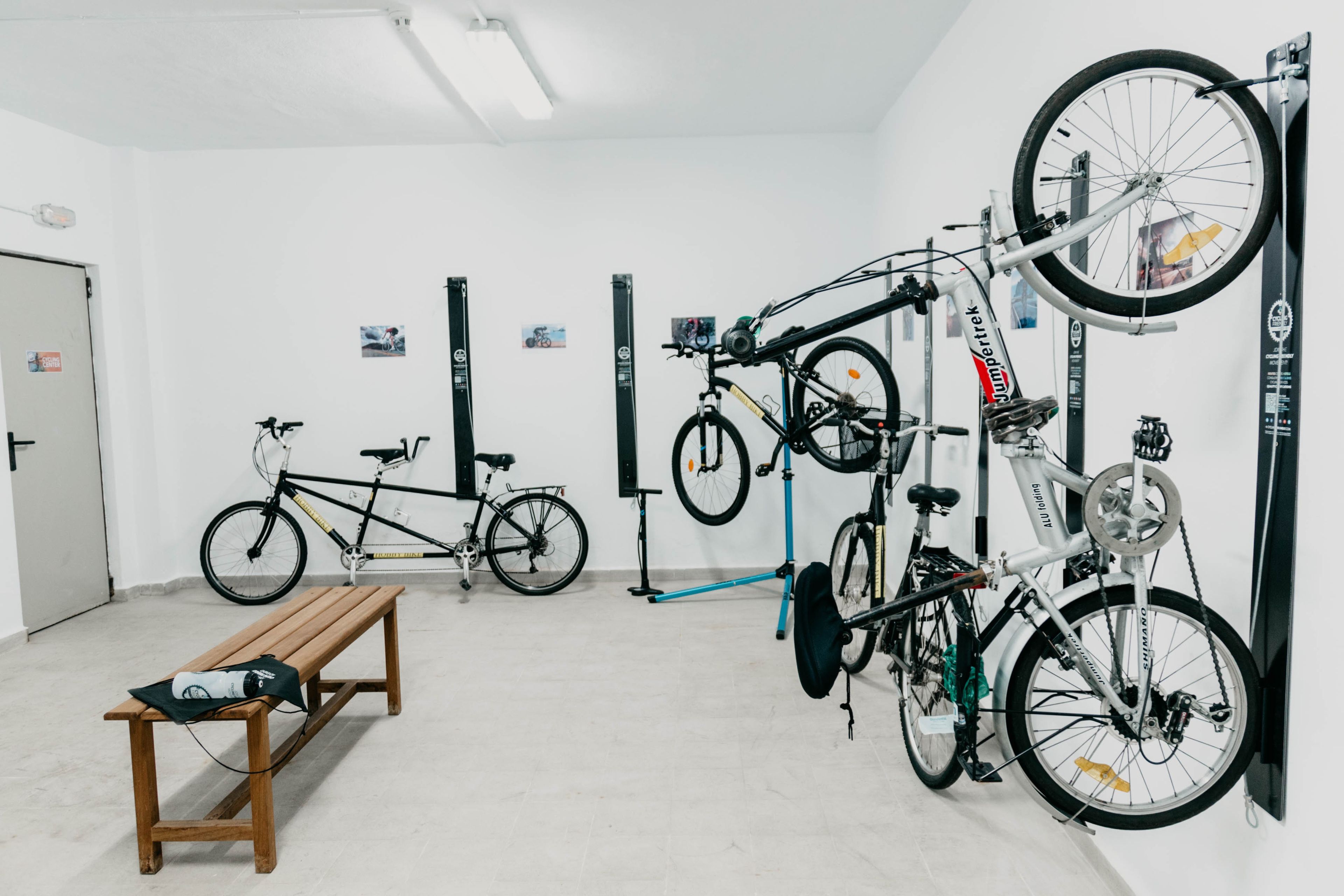 A room with bicycles mounted on walls, a bench, and a door.