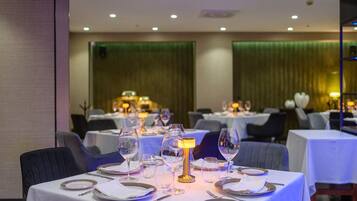 A restaurant with tables set for dining, featuring white tablecloths, plates, and wine glasses.