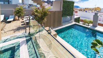 Een buitenzwembad, ligstoelen bij het zwembad