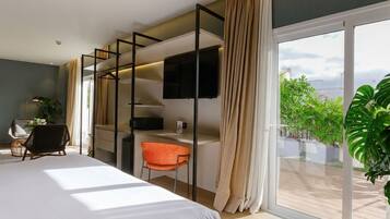 Une chambre d’hôtel moderne dotée d’un grand lit, d’un bureau, d’une chaise, d’une télévision et d’un balcon agrémenté de plantes.