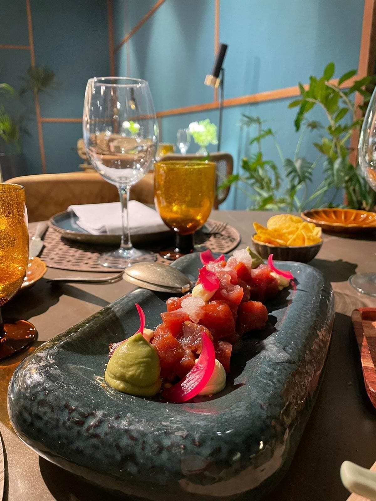 Una mesa de comedor con un plato de mariscos, una copa de vino y un cuenco de papas fritas.