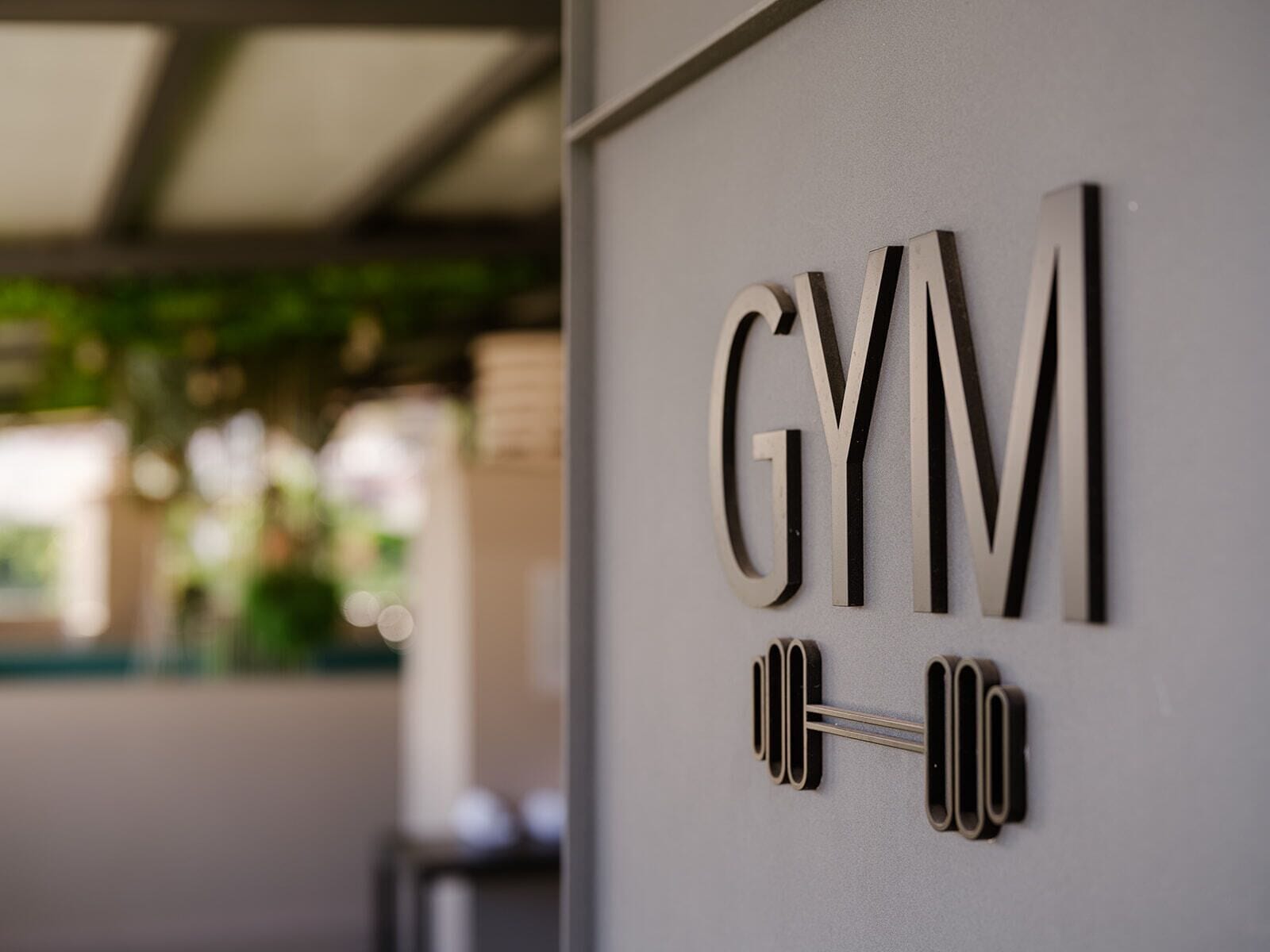A wall with the word "GYM" and a dumbbell symbol, indicating a gym facility.