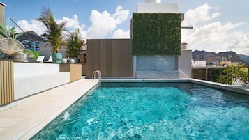 Een buitenzwembad, ligstoelen bij het zwembad