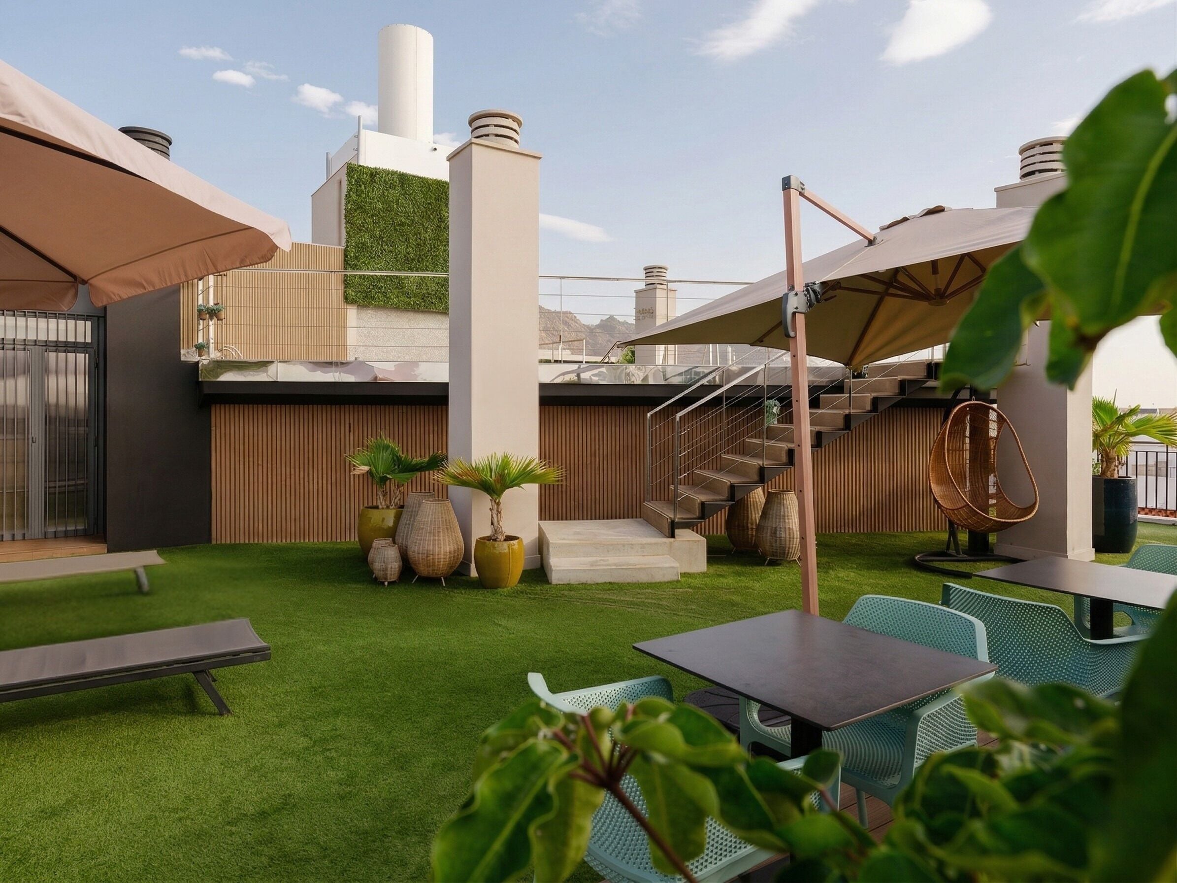 A rooftop terrace with a modern design, featuring a staircase, outdoor seating, and a green wall.