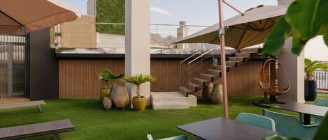 A rooftop terrace with a modern design, featuring a staircase, outdoor seating, and a green wall.