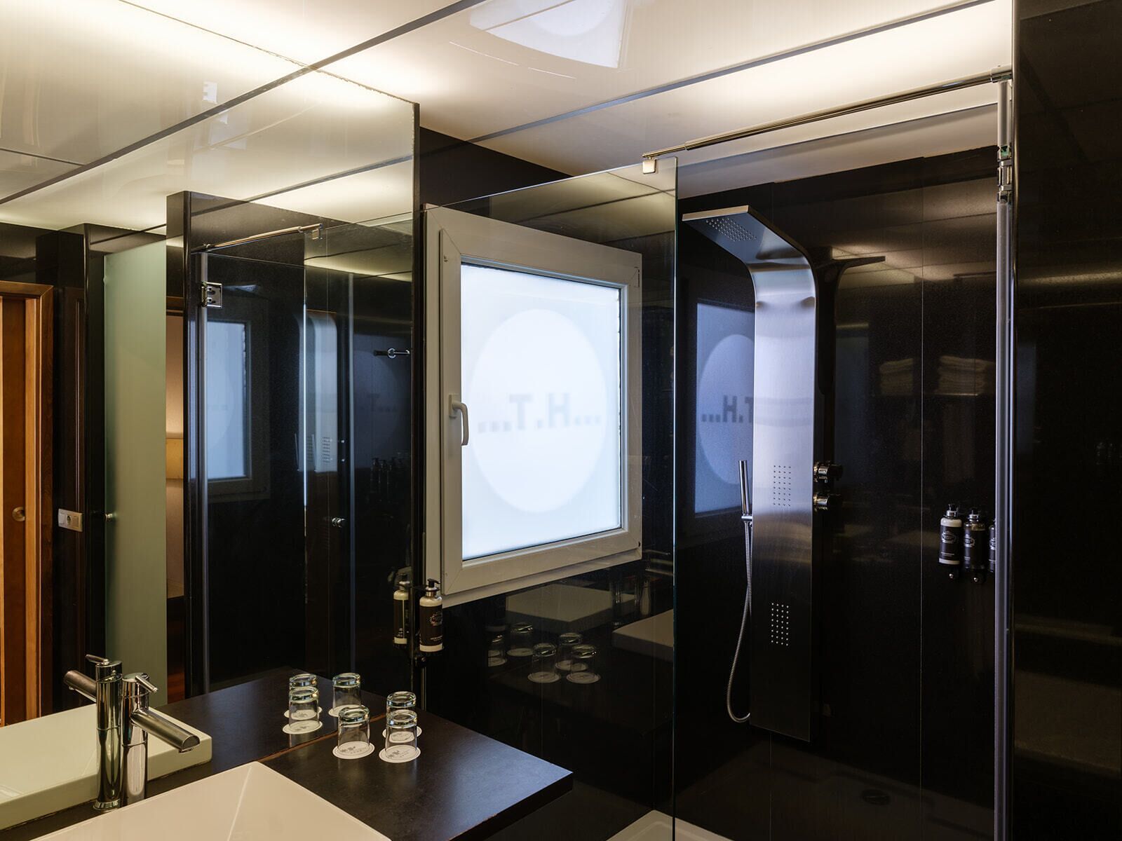 Un baño moderno con cabina de ducha de vidrio, un lavamanos con grifo cromado y una pantalla digital.