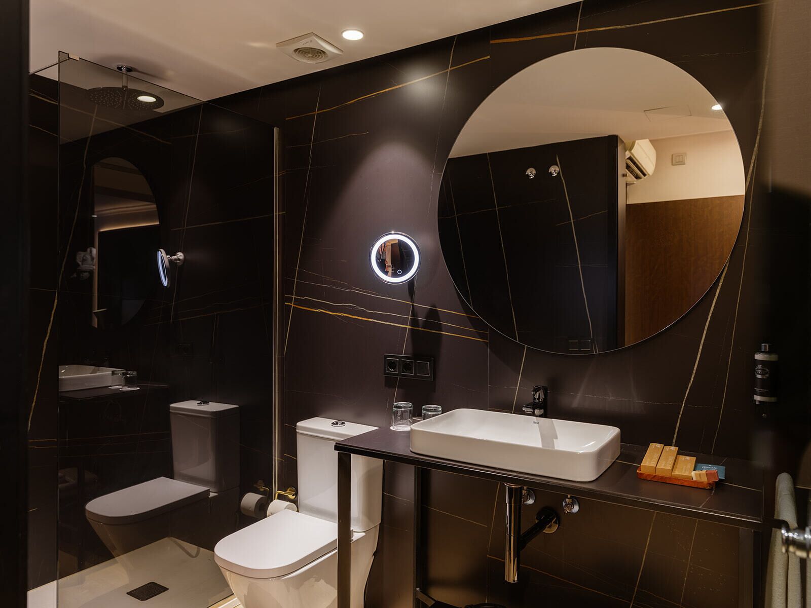 Un baño moderno con inodoro, lavamanos y espejo.