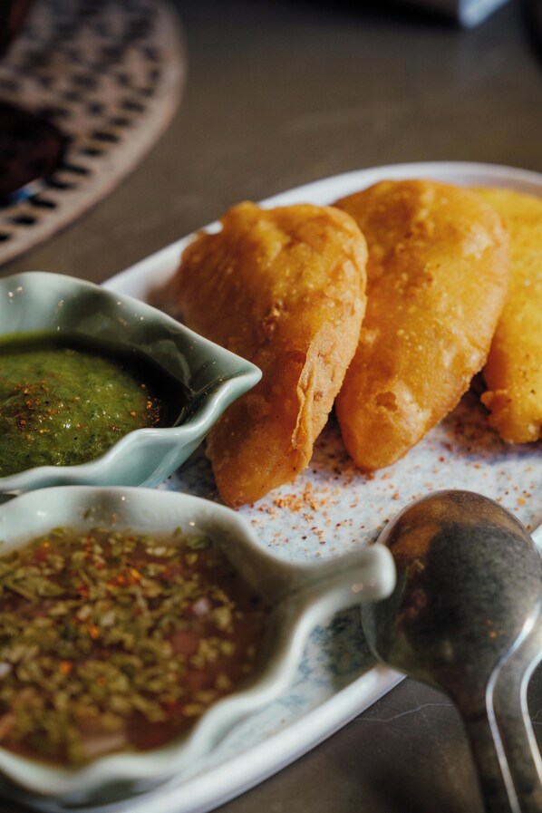 Un plato con comida frita y dos recipientes pequeños de salsas para mojar.