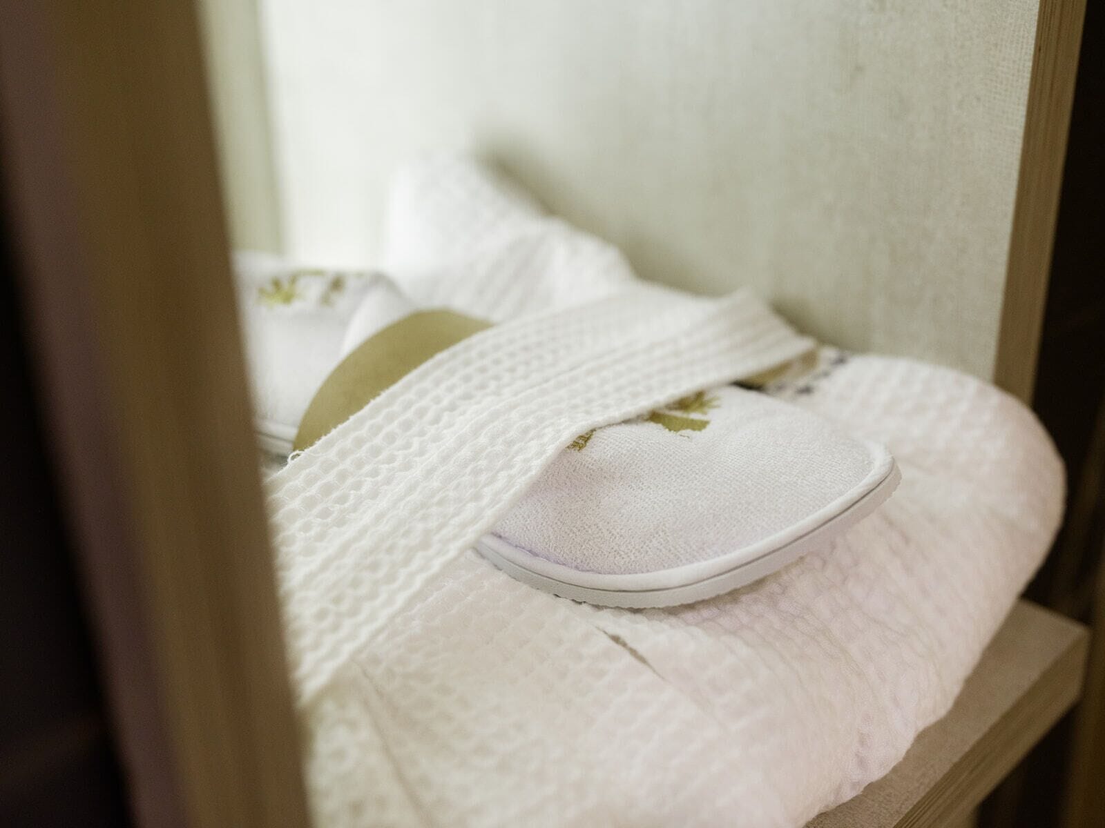 A bed with white bedding and a pillow with a floral design.