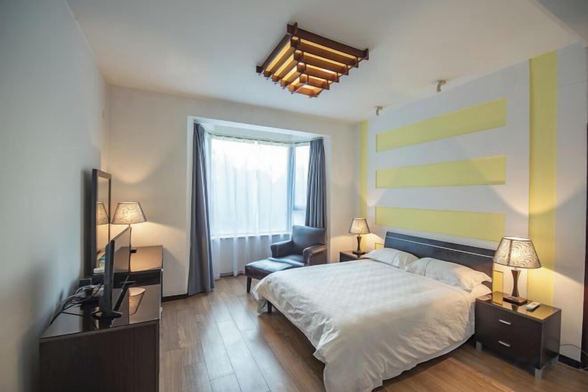 A modern hotel room with a bed, bedside tables, a desk, and a chair.