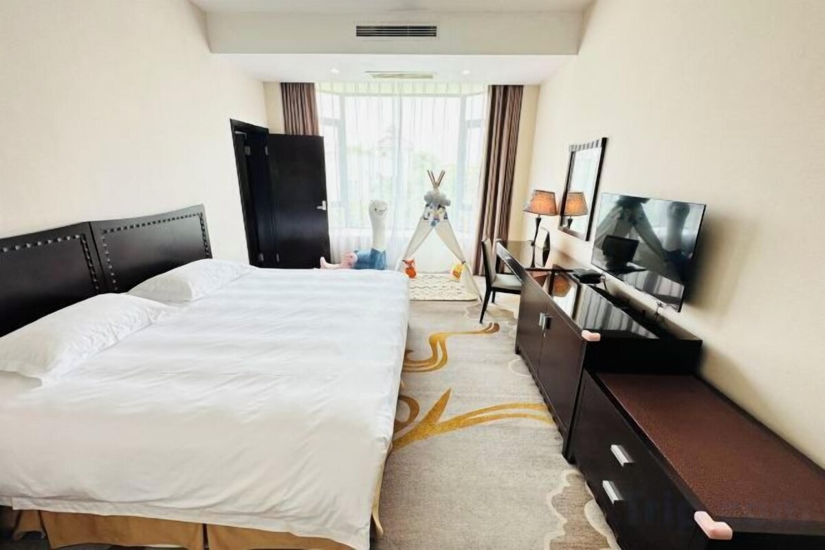 A hotel room with a bed, a TV, a desk, and a wardrobe.