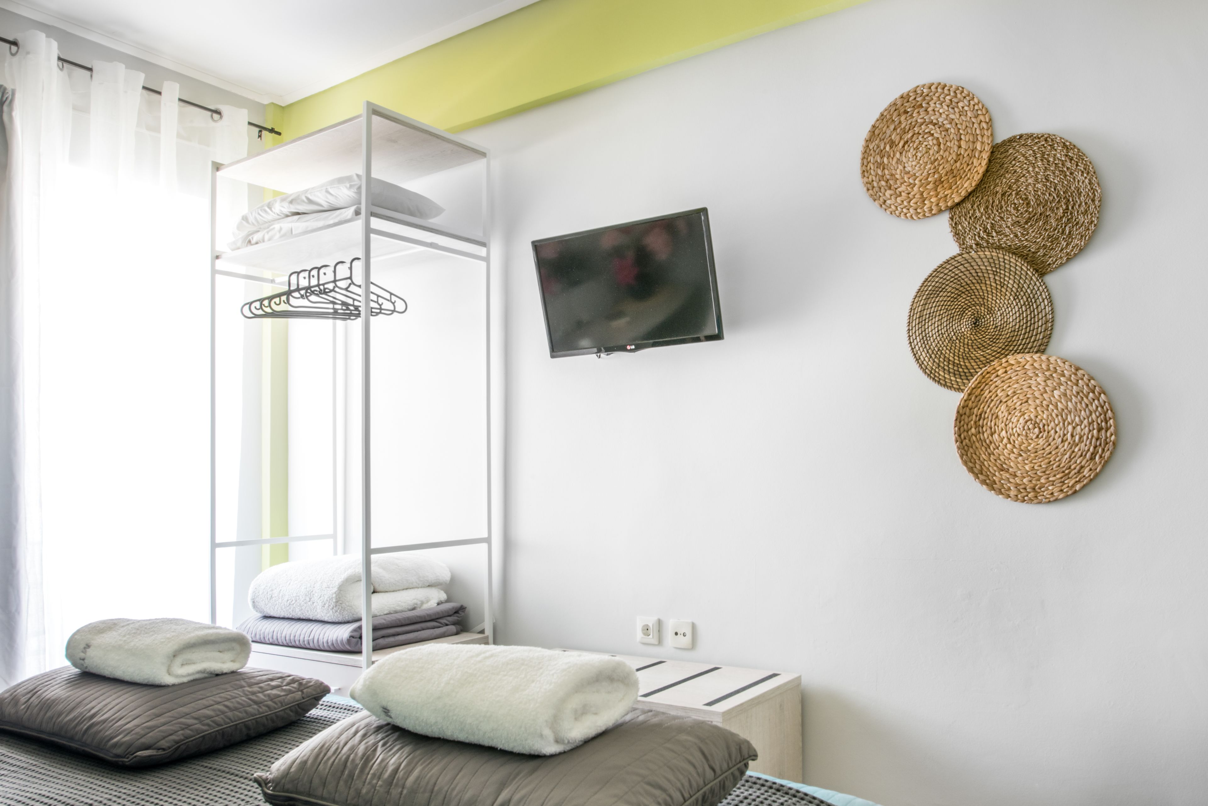 Ein modernes Zimmer mit Etagenbett, Kleiderschrank mit Platz zum Aufhängen, Flachbildfernseher und Wanddekoration aus Gewebe.
