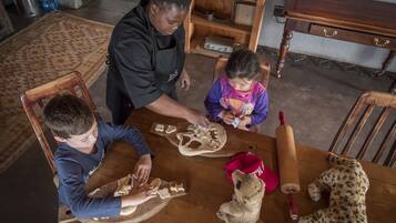 A family at a wooden dining table with a leopard plush toy and a rolling pin.