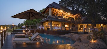 Una piscina al aire libre, sombrillas, sillones reclinables de piscina