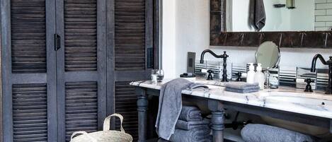 A bathroom with a dark wood door, a marble sink, a mirror, and a towel rack with folded towels.