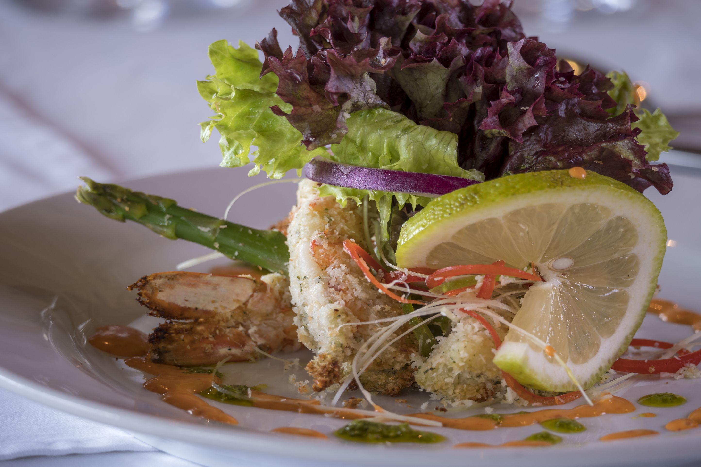 A plate of food with a slice of grilled chicken, asparagus, and a lime wedge.