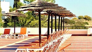 Terraço com espreguiçadeiras e guarda-sóis.