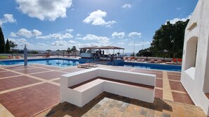 Uma área de piscina com vários espreguiçadeiras e um espaço coberto para relaxar.