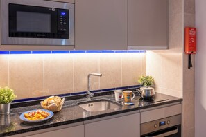 A modern kitchen with a built-in microwave, stainless steel sink, and a kettle on the counter.