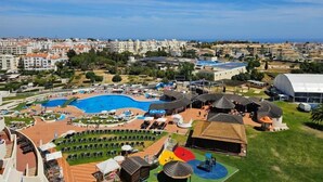 Et resort med en stor swimmingpool, udendørs siddeområder og udsigt over byens skyline.