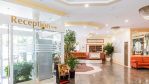 A reception area with a reception desk, a reception sign, and potted plants. - Parkhotel Frankfurt Airport (Hattersheim)