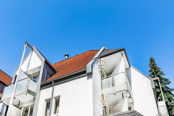 A white building with a red-tiled roof, multiple balconies, and a clear blue sky. - Parkhotel Frankfurt Airport (Hattersheim)