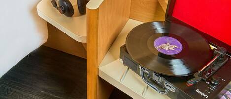 Tocadiscos con un disco de vinilo, auriculares y un enchufe sobre un estante de madera.