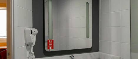 A bathroom with a white sink, a mirror, and a hand dryer.