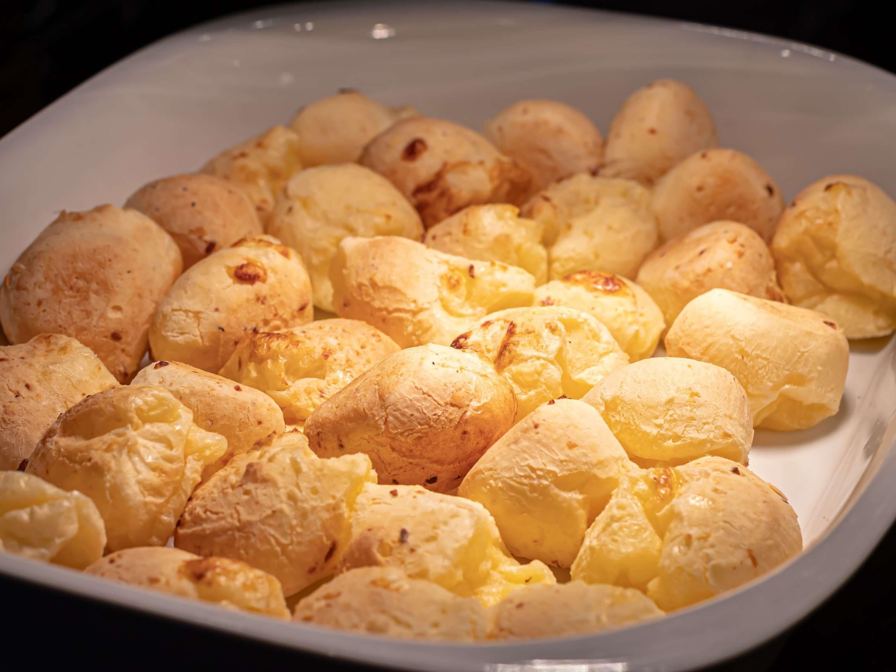 A white plate filled with golden-brown cheese puffs.