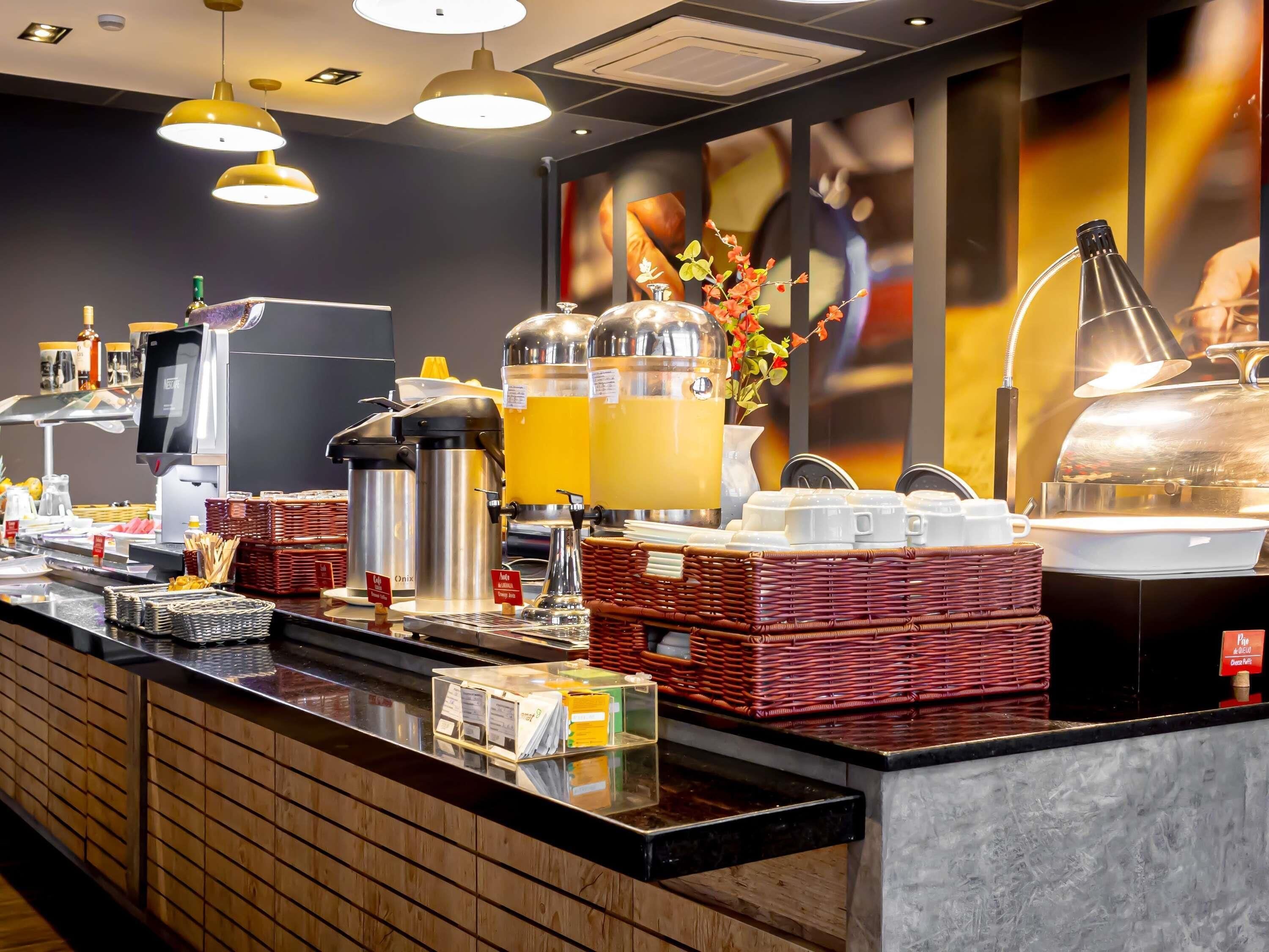 Een ontbijtbuffet met koffieautomaten, sapdispensers en diverse ontbijtartikelen.