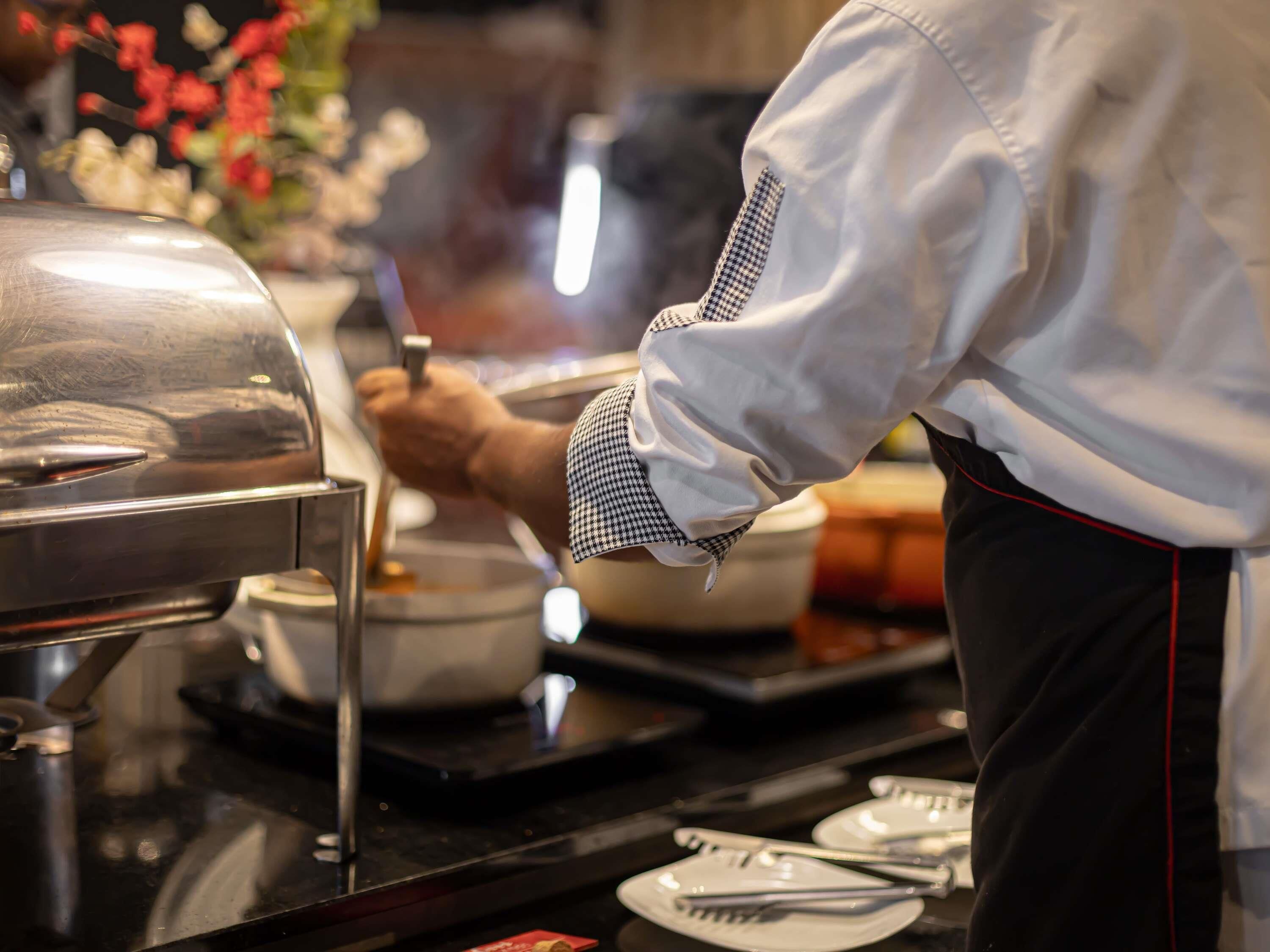 A buffet setup with a covered grill, serving utensils, and plates.