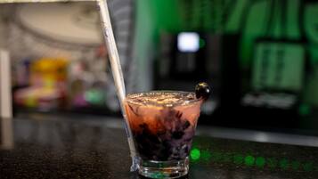 A glass of iced beverage with a straw, placed on a reflective surface.