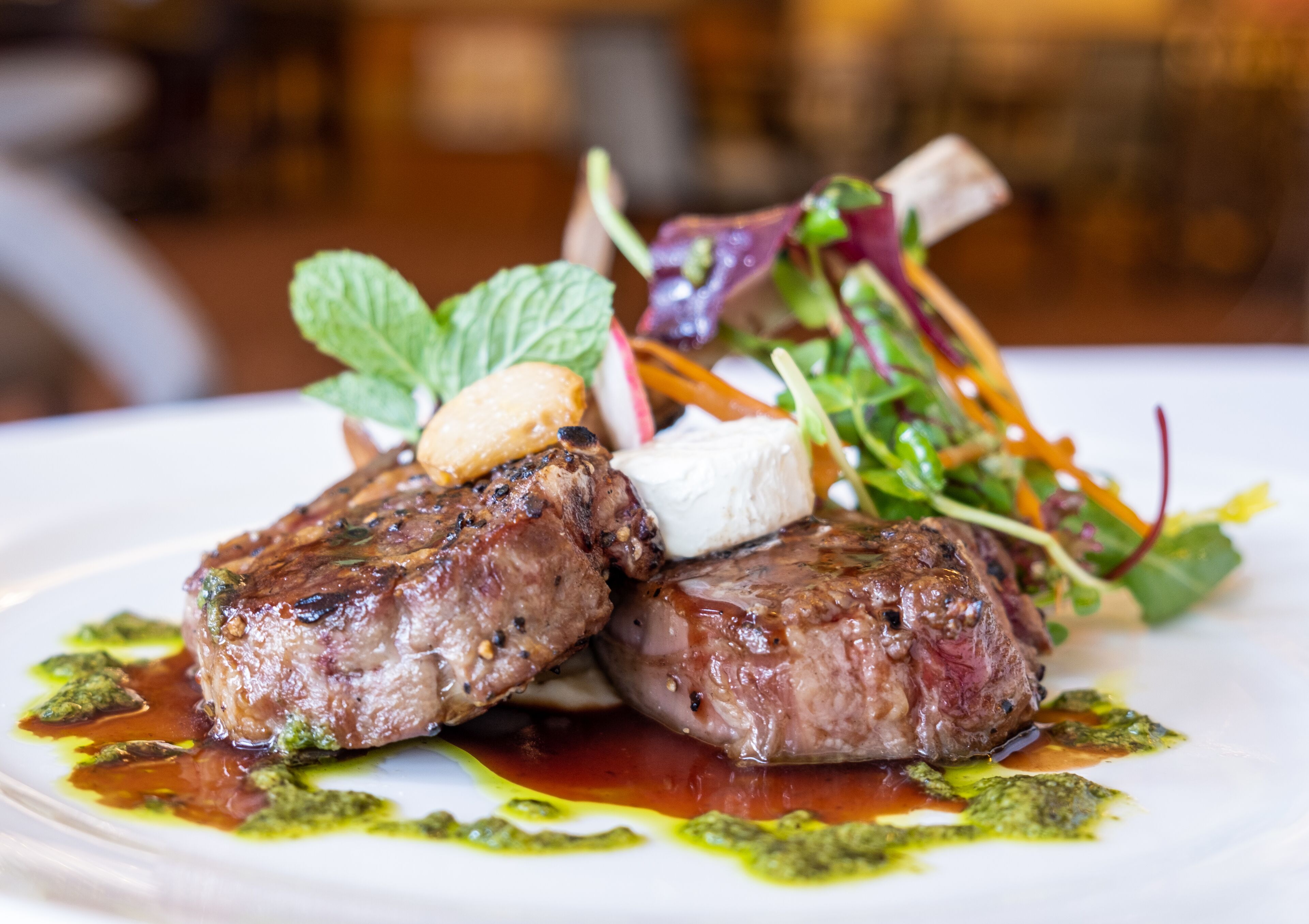 A plate of food with two grilled steaks, a dollop of butter, and a side salad.