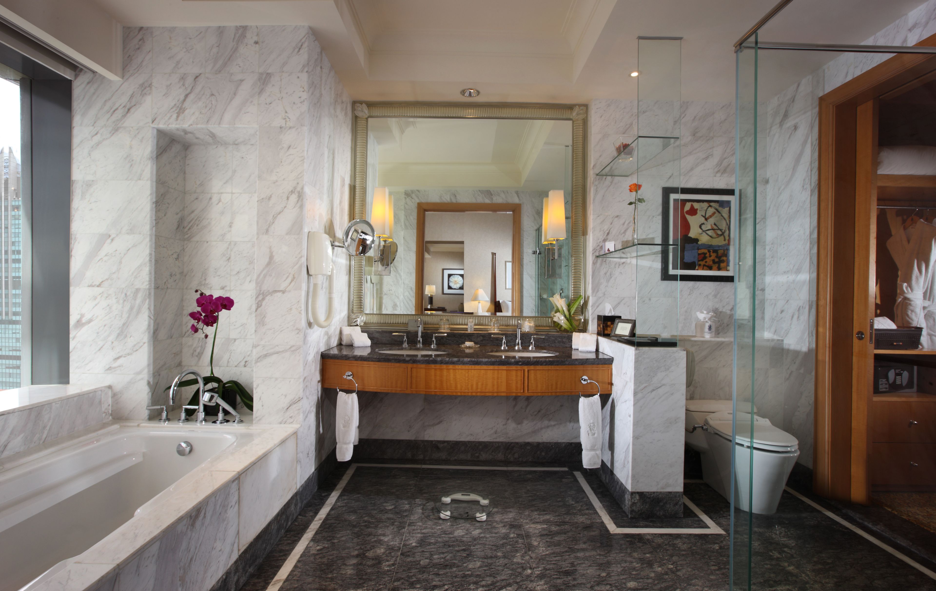 A modern bathroom with a marble sink, a bathtub, and a glass shower enclosure.