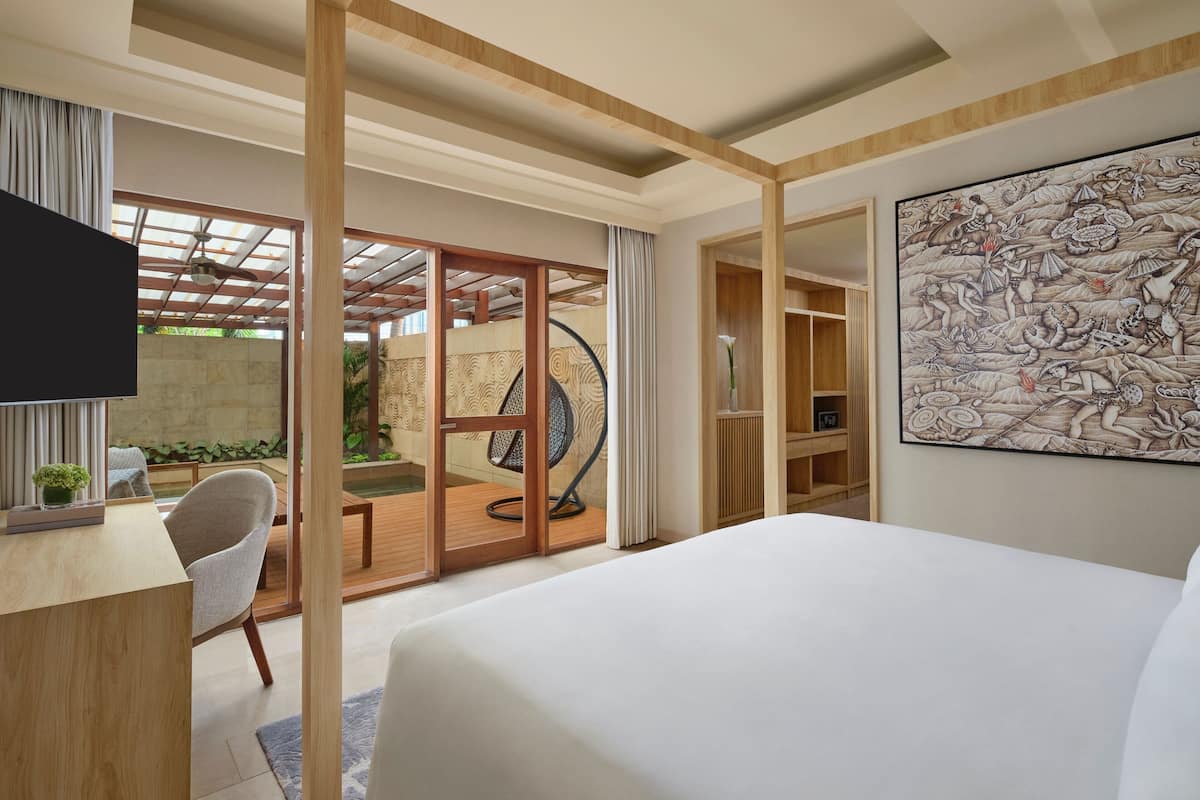 A modern hotel room with a large bed, a desk with a chair, a TV, and a large artwork on the wall.