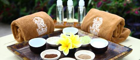 Bandeja con diversos productos de spa y una flor amarilla, rodeada de toallas enrolladas con un diseño de león.