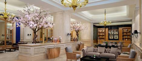 A spacious lobby with a central seating area, a bar, and a large chandelier.
