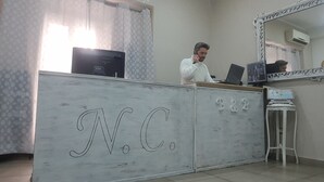 A room with a white cabinet labeled "N.C.", a laptop on the cabinet, a mirror, and a small table with a map. - Napoli Centrale (Naples)