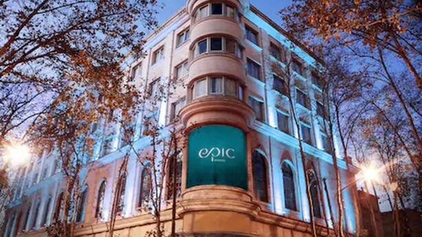Un bâtiment historique, reconnaissable à son imposante enseigne « Epic », qui présente une architecture classique avec des fenêtres en arc de cercle et une entrée située à l’angle.