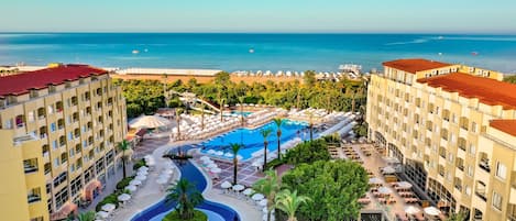A resort with a central pool, multiple balconies, and a view of the sea.