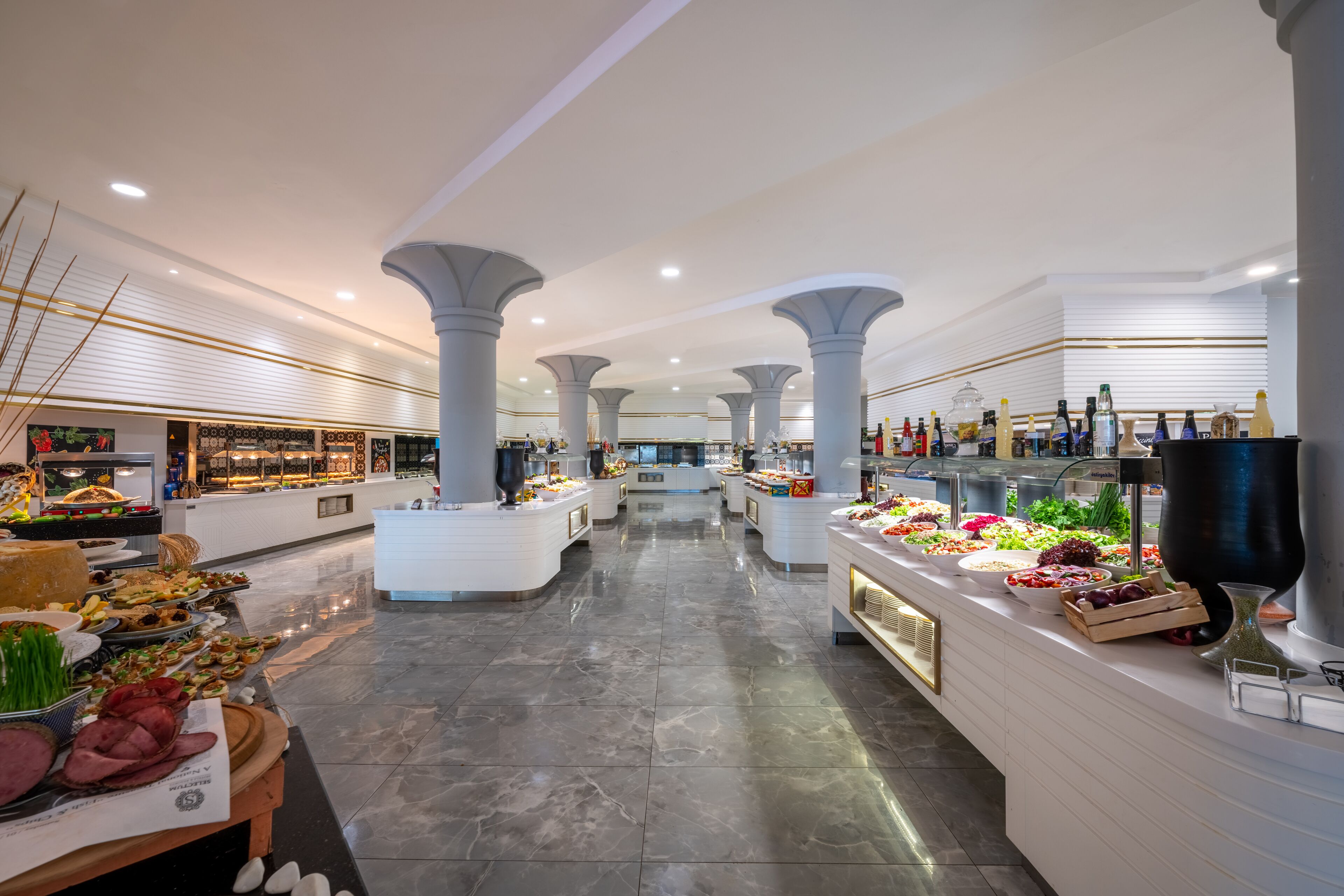 A spacious, well-lit buffet area with multiple food stations and a central walkway.