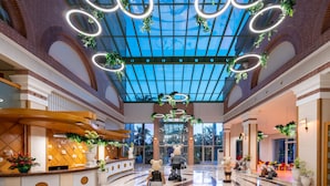 A spacious lobby with a high ceiling, circular light fixtures, and potted plants. - Selectum Family Resort Side (Manavgat)