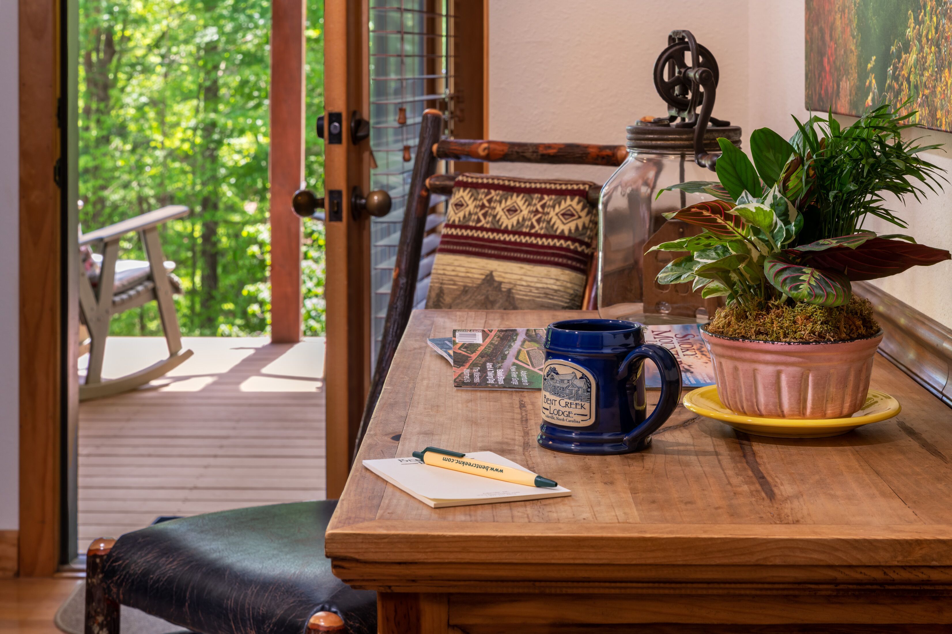 A wooden table with a blue mug, a potted plant, and a map.