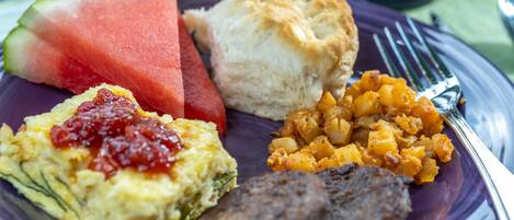 A plate with breakfast items including scrambled eggs, sausage, toast, and a slice of watermelon.