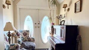 A hallway with a piano, a guitar, and a plant. - Ocean Breeze B&B (North Vancouver)