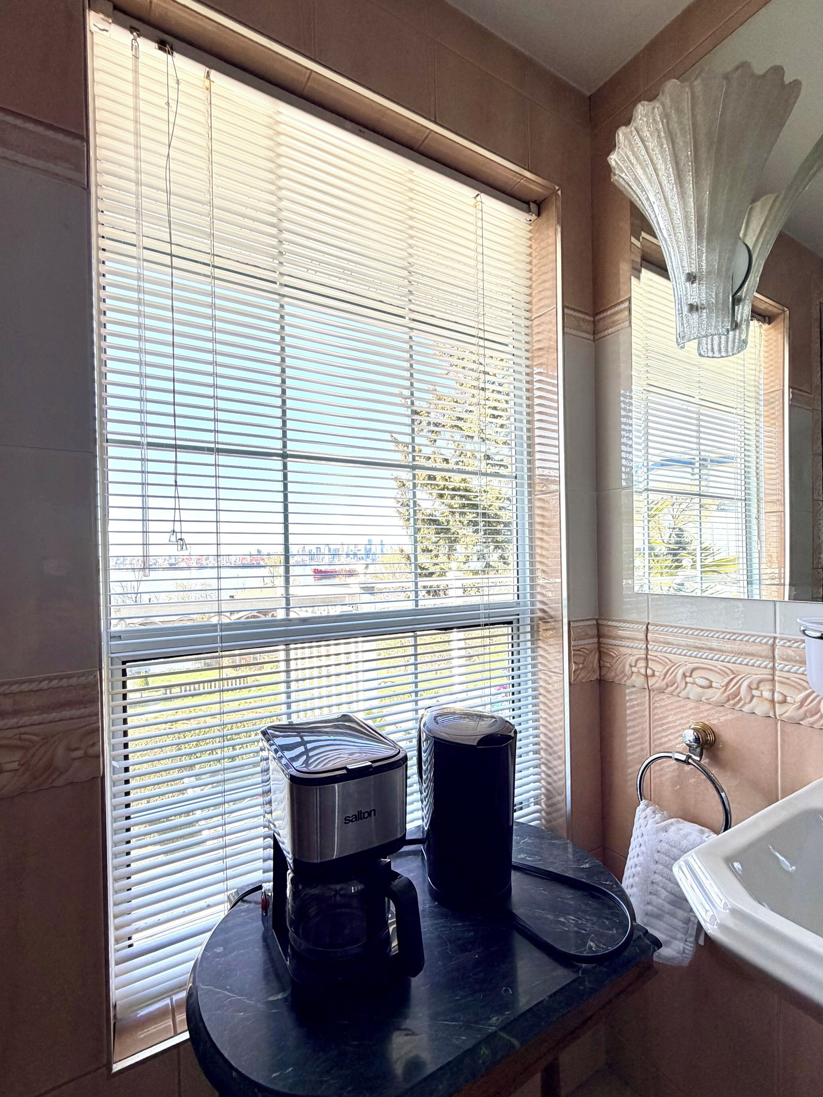 A bathroom with a sink, a mirror, and a window with blinds.