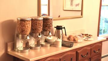 A kitchen counter with three coffee dispensers, a coffee pot, and a plate of pastries.