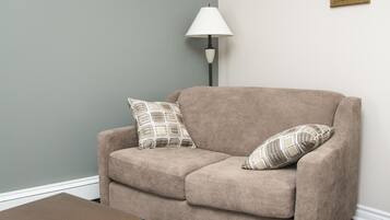 A living room with a beige sofa, a wooden coffee table, and a patterned rug.